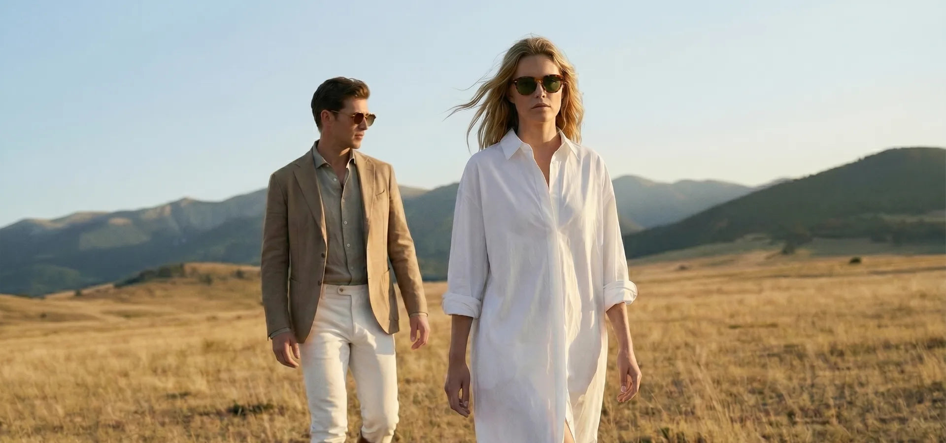 Man and woman walking in a field with mountains in the background1621243260e1af0c20-0